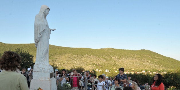 Catholic pilgrims gather kneeling around a statue of Virgin Mary, overseeing the area around a pilgrimage site near the Southern-Bosnian town of Medjugorje on June 25, 2011. The Virgin Mary is said to have appeared the first time here on June 25, 1981, to youths and is since then a magnet for Christians. Medjugorje is located in the Hercegovina region that is mostly populated by Bosnian Catholic Croats. For 30 years, the alleged phenomenon was ignored by Roman Catholic authorities until 2010, when Pope Benedict XVI issued an order to form an investigation team to search for the truth in case of Medjugorje sightings. AFP PHOTO ELVIS BARUKCIC (Photo credit should read ELVIS BARUKCIC/AFP/Getty Images)