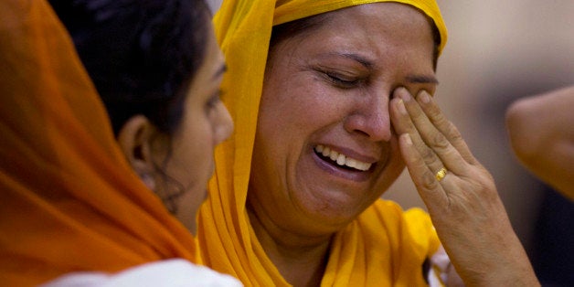 Mourners weep at the funeral and memorial service for the six victims of the Sikh temple of Wisconsin mass shooting in Oak Creek, Wis., Friday, Aug 10, 2012. The public service was held in the Oak Creek High School. Three other people were wounded in the shooting last Sunday at the temple. Wade Michael Page, 40, killed five men and one woman, and injured two other men. Authorities say Page then ambushed the first police officer who responded, shooting him nine times and leaving him in critical condition. A second officer then shot Page in the stomach, and Page took his own life with a shot to the head. (AP Photo/Jeffrey Phelps)