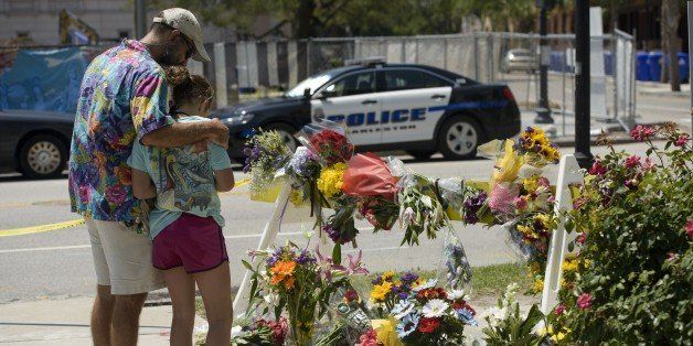 People visit a makeshift memorial near the Emanuel AME Church June 18, 2015 in Charleston, South Carolina, after a mass shooting at the Church on the evening of June 17, 2015. US police on Thursday arrested a 21-year-old white gunman suspected of killing nine people at a prayer meeting in one of the nation's oldest black churches in Charleston, an attack being probed as a hate crime. The shooting at the Emanuel African Methodist Episcopal Church in the southeastern US city was one of the worst attacks on a place of worship in the country in recent years, and comes at a time of lingering racial tensions. AFP PHOTO/BRENDAN SMIALOWSKI (Photo credit should read BRENDAN SMIALOWSKI/AFP/Getty Images)