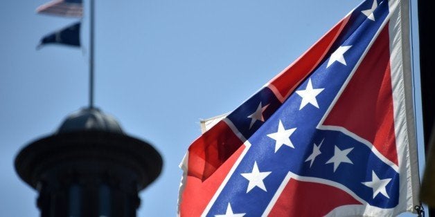 The South Carolina and American flags flying at half-staff behind the Confederate flag erected in front of the State Congress building in Columbia, South Carolina on June 19, 2015. Police captured the white suspect in a gun massacre at one of the oldest black churches in Charleston in the United States, the latest deadly assault to feed simmering racial tensions. Police detained 21-year-old Dylann Roof, shown wearing the flags of defunct white supremacist regimes in pictures taken from social media, after nine churchgoers were shot dead during bible study on Wednesday. AFP PHOTO/MLADEN ANTONOV (Photo credit should read MLADEN ANTONOV/AFP/Getty Images)