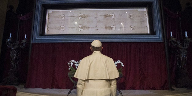 In this pool photo taken Sunday, June 21, 2015, and made available Monday, June 22, Pope Francis prays in front of the Holy Shroud, the 14 foot-long linen revered by some as the burial cloth of Jesus, on display at the Cathedral of Turin, Italy, Sunday, June 21, 2015. Francis visited the long linen with the faded image of a bearded man, during his two-day pilgrimage to Turin. (L' Osservatore Romano/Pool Photo via AP)