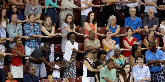 CHARLESTON, SC - JUNE 19: Thousands of people hold hands and sing 'We Shall Overcome' during a prayer vigil for the nine victims of the Emanuel AME Church shooting at the College of Charleston TD Arena June 19, 2015 in Charleston, South Carolina. Authorities arrested Dylann Storm Roof, 21, after he allegedly attended a prayer meeting at the church for an hour before opening fire and killing three men and six women. Among the dead is the Rev. Clementa Pinckney, a state senator and a pastor at the church, the oldest black congregation in America south of Baltimore, according to the National Park Service. (Photo by Chip Somodevilla/Getty Images)