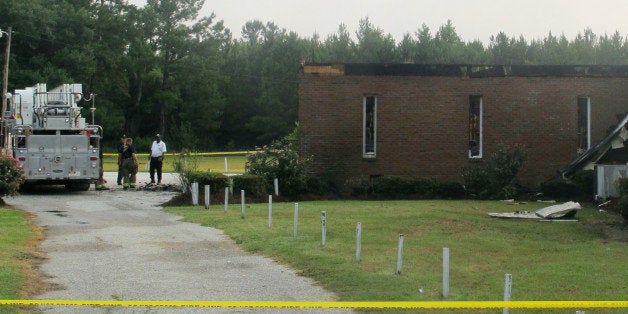 Emergency personnel continue their work at Mount Zion AME Church in Greeleyville, S.C., Wednesday, July 1, 2015, after it was heavily damaged by fire. The church was the target of arson by the Ku Klux Klan two decades ago but a law enforcement source told The Associated Press that the most recent fire was not arson. (AP Photo/Bruce Smith)