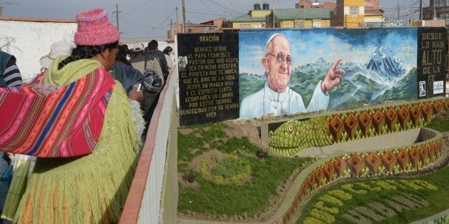 An indigenous woman is seen near a mural of Pope Francis in El Alto, Bolivia on July 3, 2015. Pope Francis will make a three-