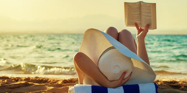 woman lying on beach and reading, sunset time, at the edge of sea, sunhat.photo taken in summer day outdoors.