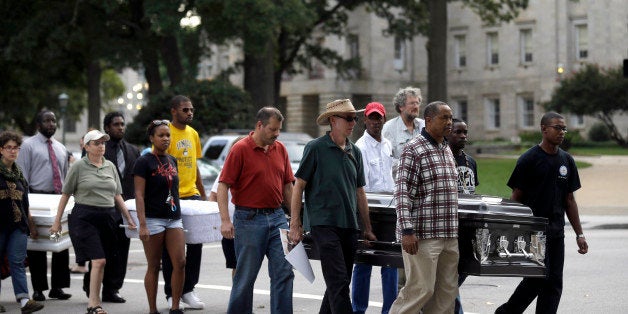 Protestors led by the North Carolina branch of the NAACP march past the state Capitol on their way to the executive mansion to demonstrate against voting law changes by the state's Republican-led legislature, Monday, Sept. 16, 2013, in Raleigh, N.C. The coffins were carried in memory to four girls killed in a church bombing in Birmingham, Ala. on Sept. 15, 1963. (AP Photo/Gerry Broome)