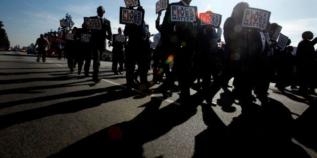 LOS ANGELES, CA - JANUARY 19: Men in Suits carrying signs that state, 'Black Lives Matter!' march in the 30th Annual Kingdom Day Parade honoring Martin Luther King Jr. on MLK Blvd. on January 19, 2015 in Los Angeles, California. Over 70,000 people were expected to participate in the parade. (Photo by Genaro Molina/Los Angeles Times via Getty Images)