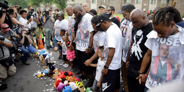 CORRECTS CITY TO FERGUSON Michael Brown Sr. along with family and friends stop to pray at a memorial to Brown's son before taking part in a parade in his son's honor Saturday, Aug. 8, 2015, in Ferguson, Mo. Sunday will mark one year since Michael Brown was shot and killed by Ferguson police officer Darren Wilson. (AP Photo/Jeff Roberson)