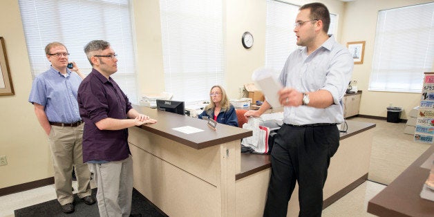 Rowan County Deputy Clerk Nathan Davis, right, informs David Moore, center, and David Ermold, left, that he won't issue them