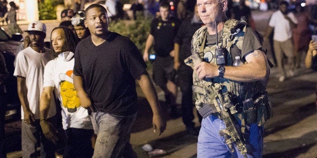 FERGUSON, MO - AUGUST 10: Oath Keepers, carrying rifles, walk along West Florrisant Street as demonstrators, marking the first anniversary of the shooting of Michael Brown, protest on August 10, 2015 in Ferguson, Missouri. Brown was shot and killed by a Ferguson police officer on August 9, 2014. His death sparked months of sometimes violent protests in Ferguson and drew nationwide focus on police treatment of black suspects. (Photo by Scott Olson/Getty Images)