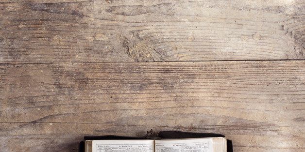 Opened bible on a wooden desk background.