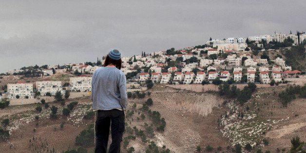 FILE - In this Wednesday, Dec. 5, 2012 file photo, a Jewish settler looks at the West bank settlement of Maaleh Adumim, from the E-1 area on the eastern outskirts of Jerusalem. In boardrooms and campuses, on social media and in celebrity circles, momentum seems to be growing for a global pressure campaign on Israel. The atmosphere recalls the boycotts that helped demolish apartheid South Africa a quarter century ago. Israel and its partisans can be expected to mount a ferocious defense, but their public relations Achilles' heel may be the Jewish settlements in the West Bank. (AP Photo/Sebastian Scheiner, File)