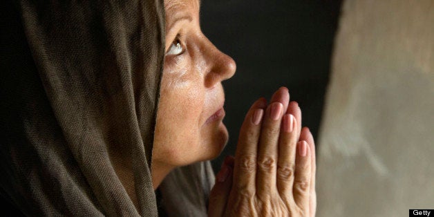 Praying mature woman folding hands in old church