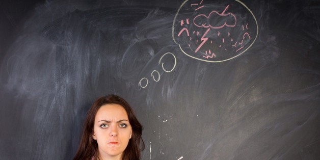 Angry young woman glaring at the camera in a depiction of rage as shown by the hand-drawn diagram of a bolt of lightning and thunder on the chalkboard alongside her