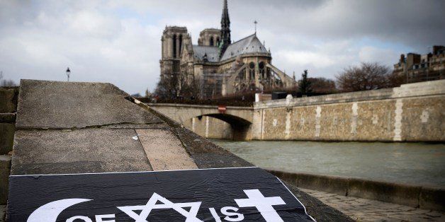 A poster by French street artist Combo is pictured after being stuck on the Quai de la Tournelle, near the Arab World Institute (IMA) on February 8, 2015 in Paris, displaying Combo's message on the coexistence of religions, using intertwined symbols of the Muslim, Jewish and Catholic religions to write the word 'Coexist'. Combo stuck and distributed posters in front of the Arab World Institute (IMA) in Paris on February 8, supported by the institution, after claiming to have been attacked because of his message on the coexistence of religions. Combo said he was attacked on January 31 at Paris' Porte Doree district by four men while he was putting on a wall a poster of himself photographed in a djellaba and associated with the word 'Coexist', using intertwined symbols of the Muslim, Jewish and Catholic religions. The Notre-Dame cathedral is seen behind. AFP PHOTO / JOEL SAGET (Photo credit should read JOEL SAGET/AFP/Getty Images)