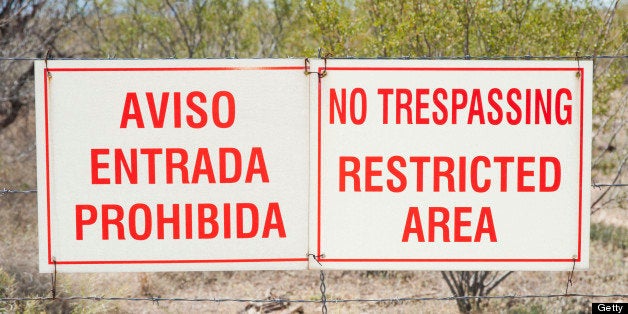 No Trespassing signs in both English and Spanish hang from a fence on the outskirts of Tucson, Arizona where illigal immigrants are known to wander.