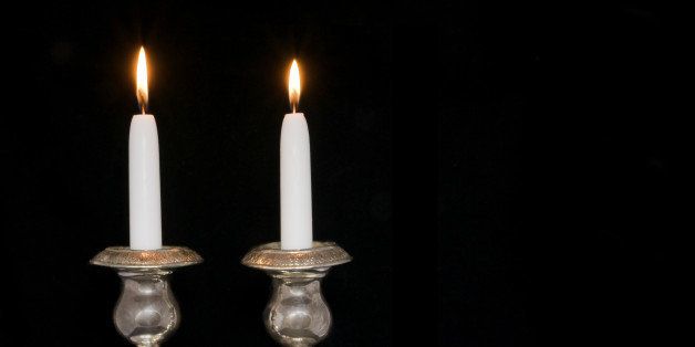 Two lighted sabbath candles isolated on a black background; horizontal view. Room for text, copy space.