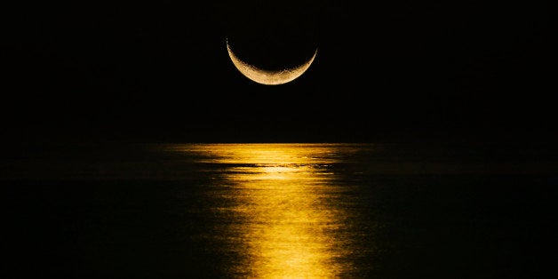 Crescent moon reflecting in sea