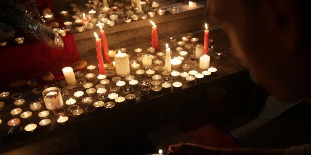A man lights a candle at a vigil in Tamar Park for the victims of the Paris terror attacks in Hong Kong on November 16, 2015.
