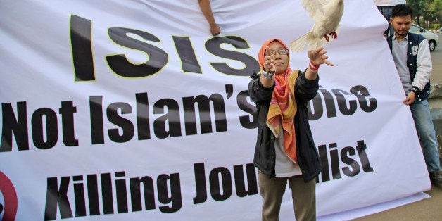 A Muslim woman releases a dove as a symbol of peace during a rally against the Islamic State group, in Jakarta, Indonesia, Friday, Sept. 5, 2014. The banner reads: "ISIS is not Islam's voice. Stop Killing journalist." (AP Photo/Tatan Syuflana)