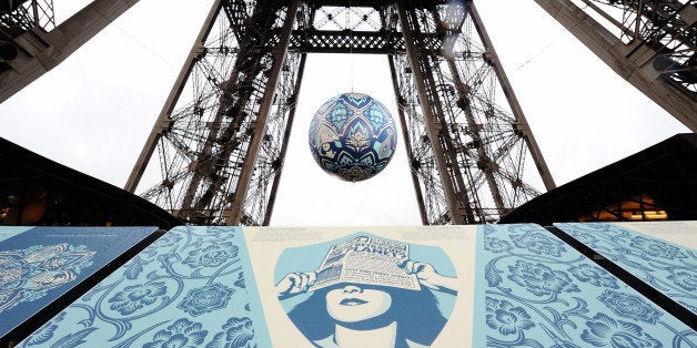 American street artist Shepard Fairey, aka Obey, 's latest piece 'Earth Crisis', a giant sphere themed on environment hangs between the first and second floor of the Eiffel Tower in Paris, Friday, Nov. 20, 2015. Obey's art piece which weighs 2,3 tons will be displayed until Nov. 26 as Paris will be hosting the climate change conference from Nov. 30-Dec. 11, 2015. (AP Photo/Binta Epelly)