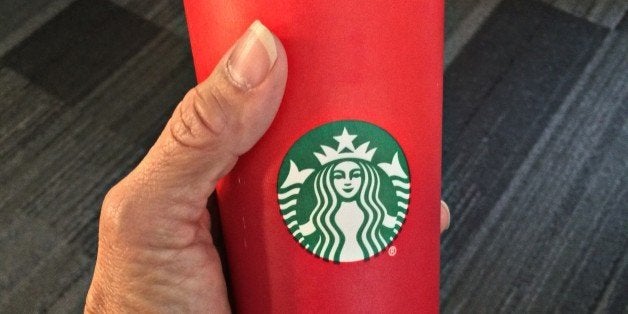 This November 9, 2015 photo shows a consumer holding the 2015 Starbucks holiday cup in Washington, DC. The unadorned red cup which debuted November 1 came under fire for its lack of design. Creating a culture of belonging, inclusion and diversity is one of the core values of Starbucks, and each year during the holidays the company aims to bring customers an experience that inspires the spirit of the season, the company wrote in a press release. Starbucks will continue to embrace and welcome customers from all backgrounds and religions in our stores around the world.AFP PHOTO/ KAREN BLEIER (Photo credit should read KAREN BLEIER/AFP/Getty Images)