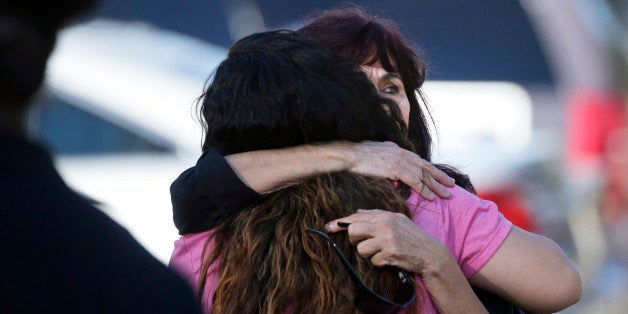 Teresa Hernandez, facing camera, is comforted by a woman as she arrives at a social services center in San Bernardino, Calif.