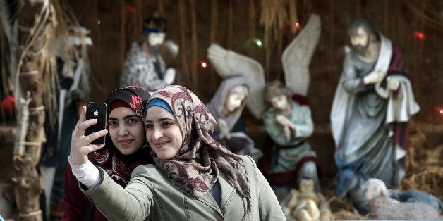 Muslim women take a selfie in front of the giant Christian manger displayed on the Manger Square in front of the Church of th