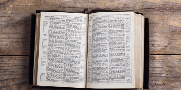 Opened bible on a wooden desk background.