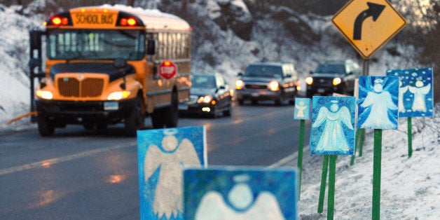 FILE - In this Jan. 3, 2013, file photo, a bus traveling from Newtown, Conn., to Monroe stops near 26 angel signs posted along the roadside in Monroe, Conn., on the first day of classes for Sandy Hook Elementary School students since the Dec. 14, 2012, shooting. The massacre in Newtown, in which a mentally troubled young man killed 26 children and teachers, served as a rallying cry for gun-control advocates across the nation. But in the three years since, many states have moved in the opposite direction, embracing the National Rifle Associationâs axiom that more âgood guys with gunsâ are needed to deter mass shootings. (AP Photo/Jessica Hill, File)