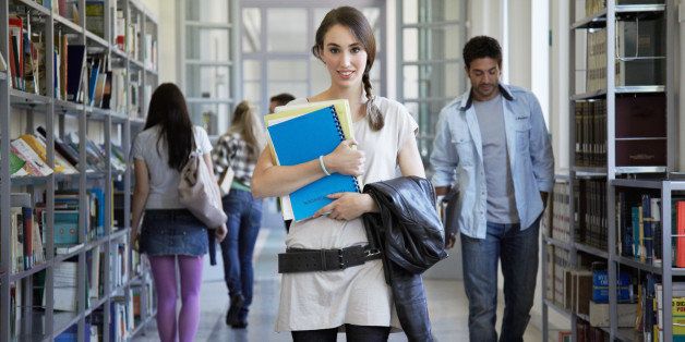 person in education, university, college, student, casual, day, education, library, book, stack, bookshelf, indoors, in a row, corridor, people, daylight, on the move smiling, looking at camera, cheerful, toothy smile,holding, portrait, people, walking, standing, T-shirt, belt, holding on chest, folders