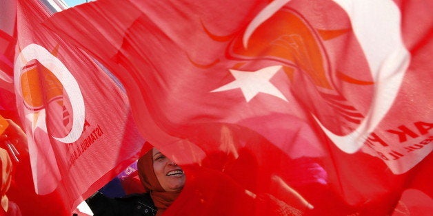 A supporter of Turkish Prime Minister and leader of the Justice and Development Party (AKP), Ahmet Davutoglu, waves her national and AKP flags during a rally to welcome Davutoglu at Ataturk airport, in Istanbul, Tuesday, Nov. 3, 2015. The ruling Justice and Development Party, or AKP, secured a stunning victory in Sunday's snap parliamentary election, sweeping back into single-party rule only five months after losing it. (AP Photo/Hussein Malla)