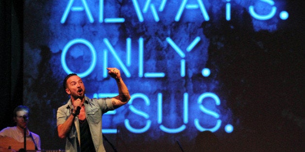 In this July 14, 2013 photo, Pastor Carl Lentz, foreground, leads a Hillsong NYC Church service at Irving Plaza in New York. With his half-shaved head, jeans and tattoos, Lentz doesn't look like the typical religious leader. But with its concert-like atmosphere and appeal to a younger demographic, his congregation, Hillsong NYC, is one of the fastest growing evangelical churches in the city. (AP Photo/Tina Fineberg)