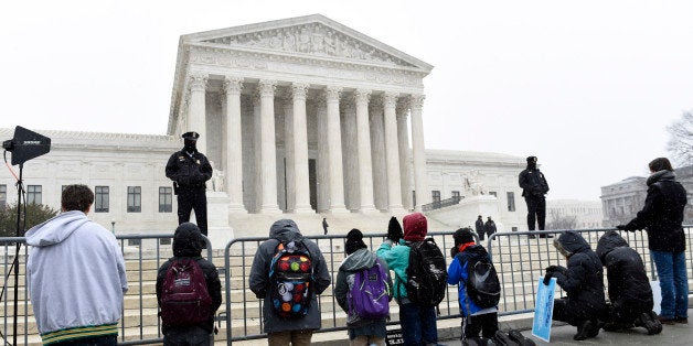 People kneel outside the Supreme Court in Washington, Friday, Jan. 22, 2016, during the March for Life 2016, the annual rally