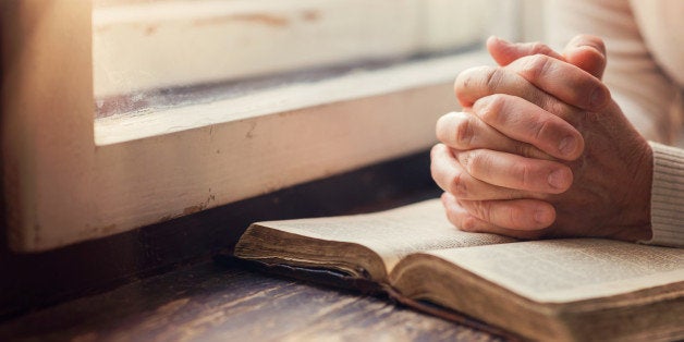 Hands of an unrecognizable woman with Bible praying