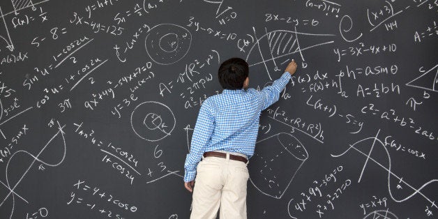 Ten year old boy at chalkboard full of trigonometry, algebra, and calculus problems.