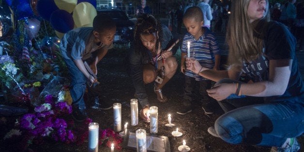 People in Roanoke participate in a candlelight vigil placing their candles near the memorial shrine of balloons and flowers o