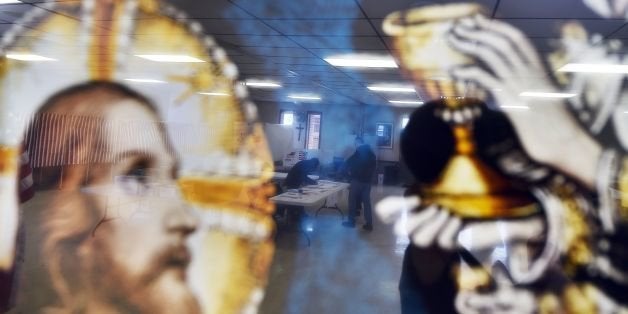 A local resident is reflected on a religious picture as he votes for the first US presidential primary at a church in Concord, New Hampshire, on February 9, 2016.New Hampshire voters headed to polls at the snowy break of day on February 9 for the crucial first US presidential primary, with Donald Trump chasing victory and Hillary Clinton looking to narrow the gap on Bernie Sanders. The northeastern state, home to just 1.3 million people, sets the tone for the primaries -- and could shake out a crowded Republican field as the arch-conservative Senator Ted Cruz and establishment candidates led by Marco Rubio battle for second place behind the frontrunner Trump. / AFP / Jewel Samad (Photo credit should read JEWEL SAMAD/AFP/Getty Images)