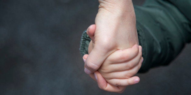 Child holding mother's hand. 