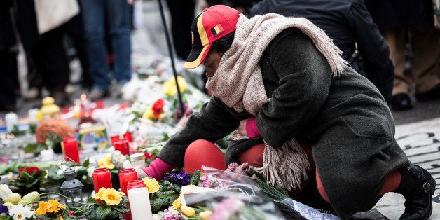 A woman lights a candle at a memorial for victims of attacks in Brussels on Wednesday, March 23, 2016. Belgian authorities were searching Wednesday for a top suspect in the country's deadliest attacks in decades, as the European Union's capital awoke under guard and with limited public transport after scores were killed and injured in bombings on the Brussels airport and a subway station. (AP Photo/Valentin Bianchi)