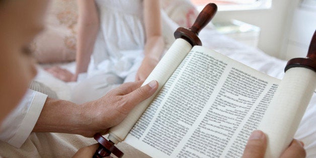 Family reading Torah scrolls together