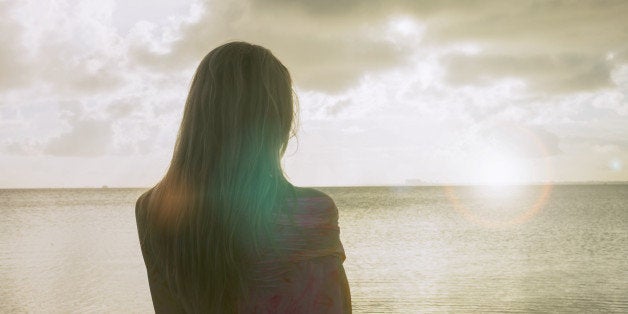 Woman on the beach watching the horizon