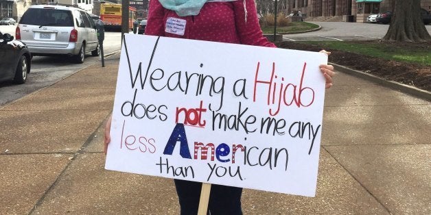 A woman holds a sign in protest after a rally for Republican Presidential candidate Donald Trump at the Peabody Opera House o