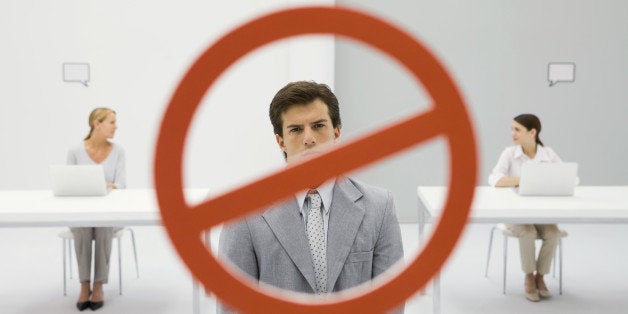 Warning sign across businessman in office, two women sitting with laptops in background