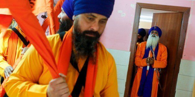 Saffron-robed man Panj Pyare (R) holds a sword before taking part in the 'Nagar Kirtan' procession, a Sikh Indian costume, in Hospitalet del Llobregat, near Barcelona, on April 10, 2016. / AFP / PAU BARRENA (Photo credit should read PAU BARRENA/AFP/Getty Images)