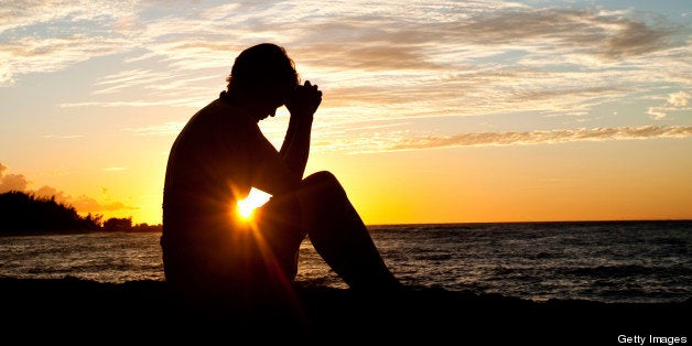 A woman deep in thought sitting by the sea. Prayer.