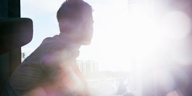 silhouette of man looking out window with flare