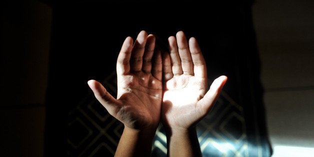 A muslim woman making dua(prayers) as light falls on her palm.