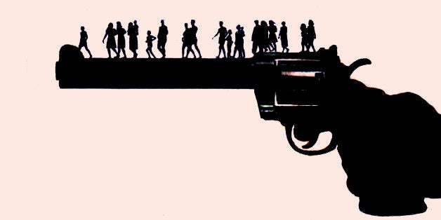Large hand holding gun with people walking along barrel