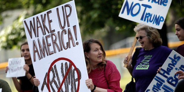 Demonstrators hold signs as they protest against U.S. Republican presidential candidate Donald Trump nearby where he and New Jersey Governor Chris Christie were to hold a fundraising event in Lawrenceville, New Jersey, U.S., May 19, 2016. REUTERS/Mike Segar